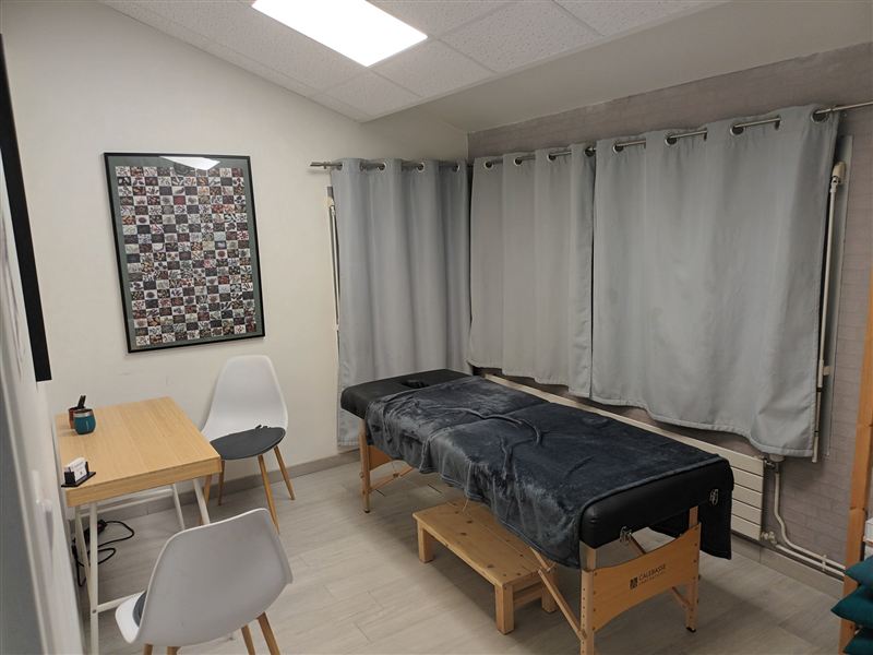 Local en temps partagé du Centre Vitalité 85 : table de massage devant la fenêtre, bureau et chaises